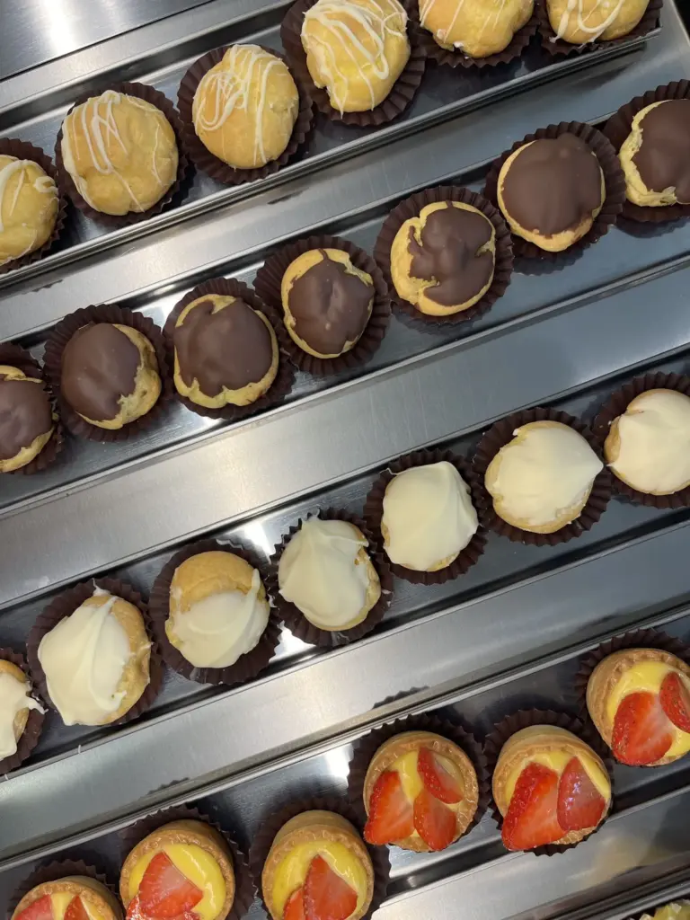 Pasticcini in vetrina: bignè glassati e cestini con fragole