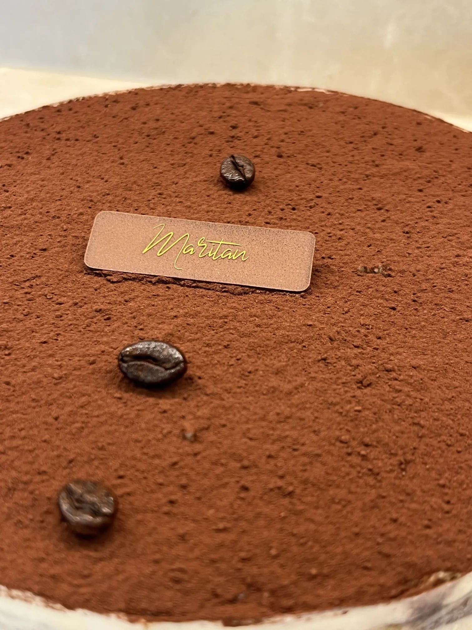 Dettaglio del tiramisù con cacao, chicchi di caffè e targhetta Maritan