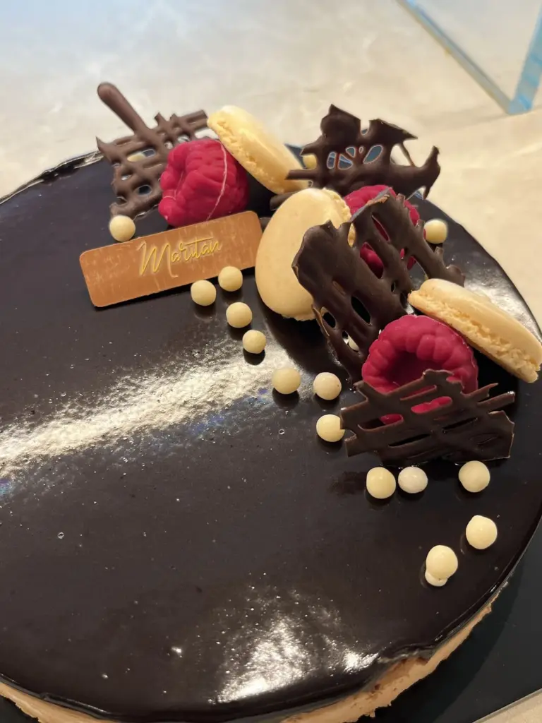 Dettaglio della torta al cioccolato con lamponi, macaron e decorazioni in cioccolato