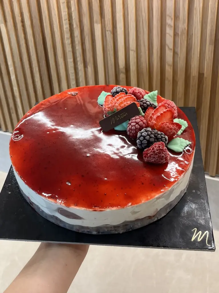 Torta con glassa rossa e frutti di bosco davanti alla boiserie in legno